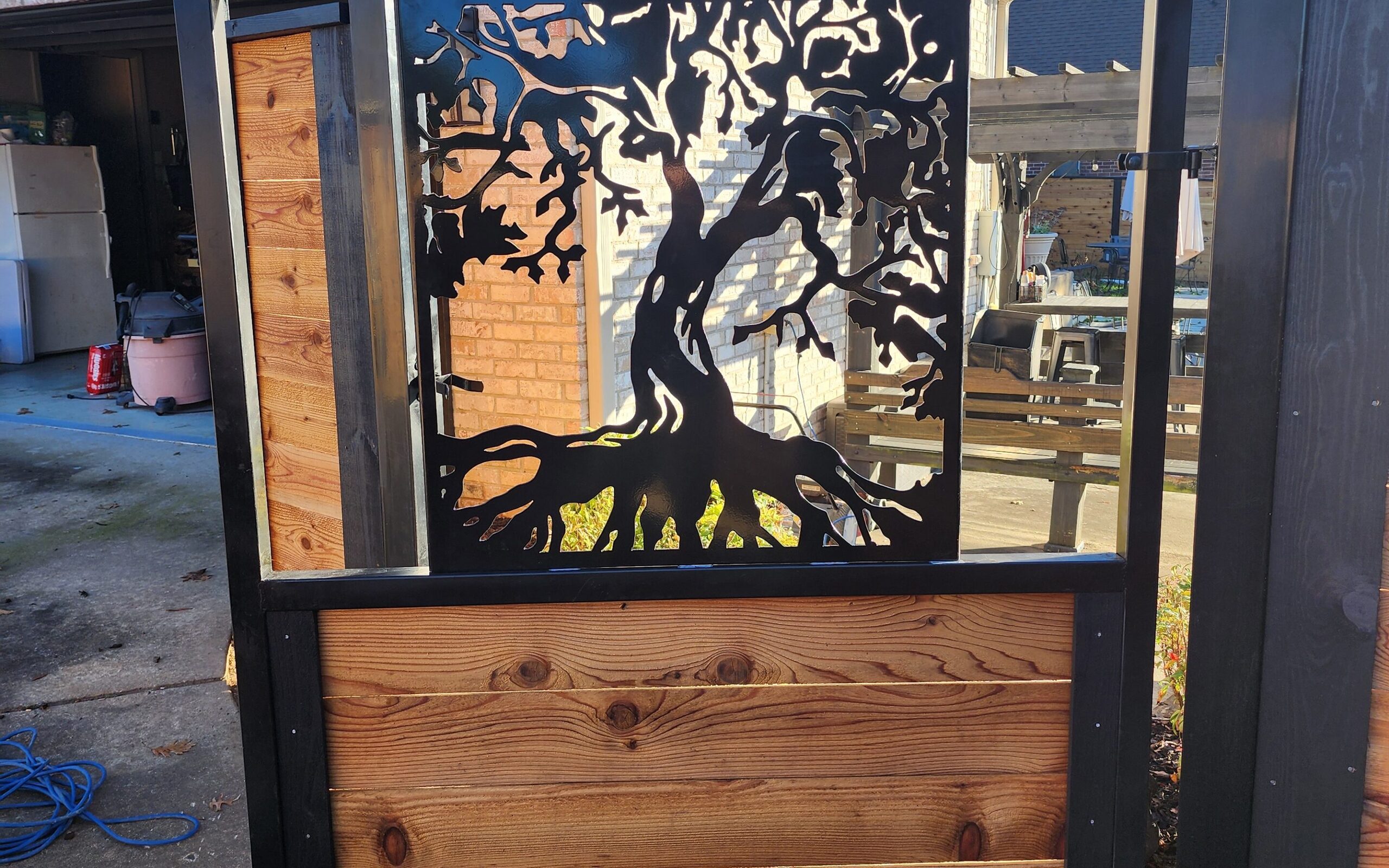 Custom metal tree-of-life gate framed in cedar